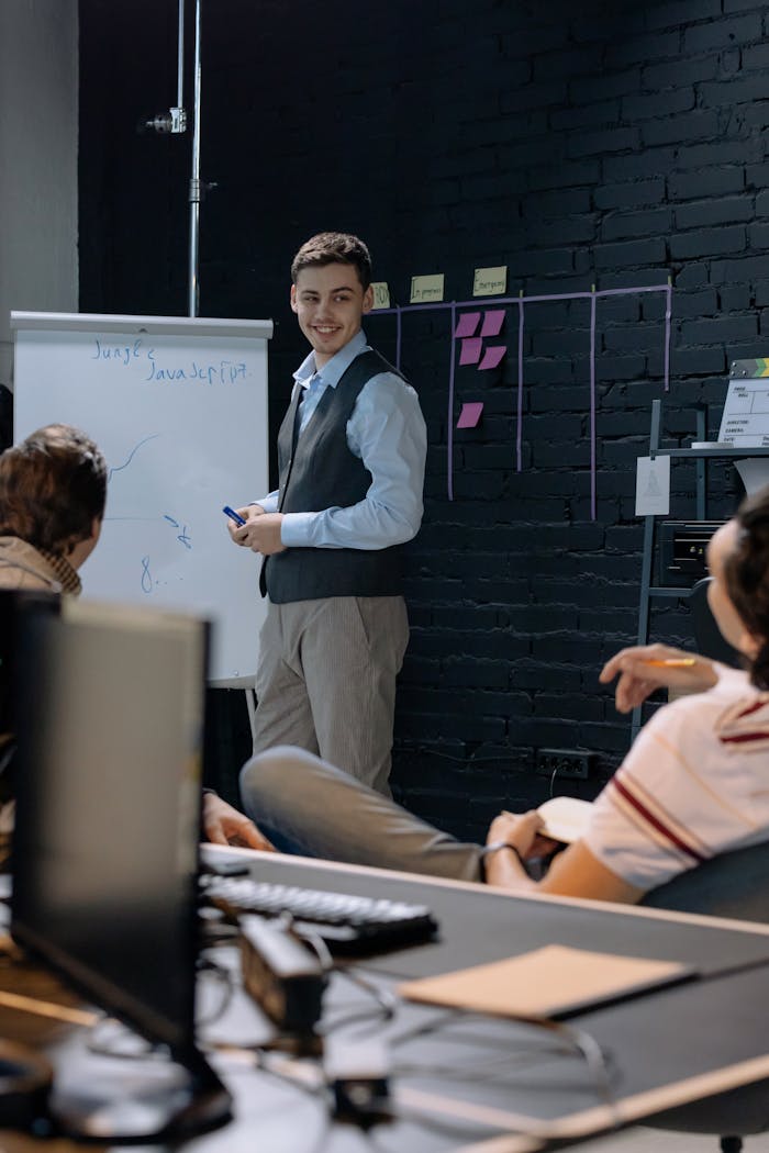 Young professionals discussing work in an office space while using a whiteboard for presentations and planning.